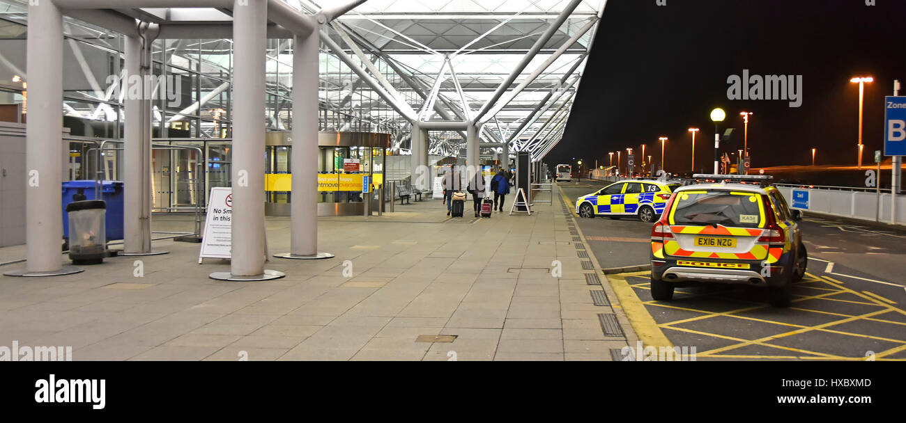 Entrance to Stansted Airport terminal building UK Airport security Essex police cars and passengers outside front on cold winter night Stock Photo