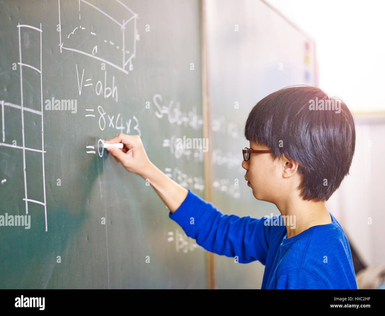 asian grade school student solving a geometry problem on chalkboard in math class. Stock Photo
