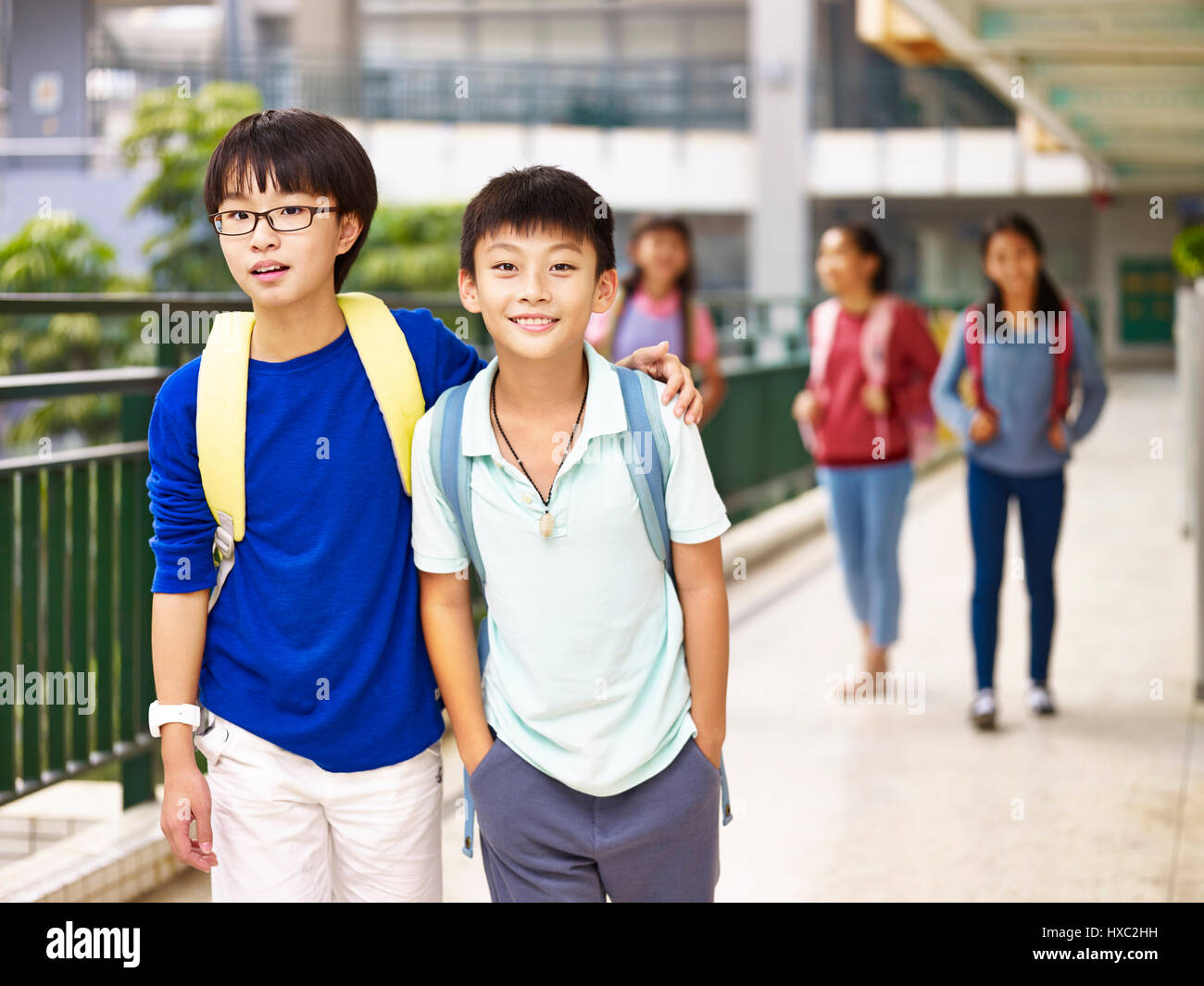 asian primary school students walking in hallway of classroom building. Stock Photo
