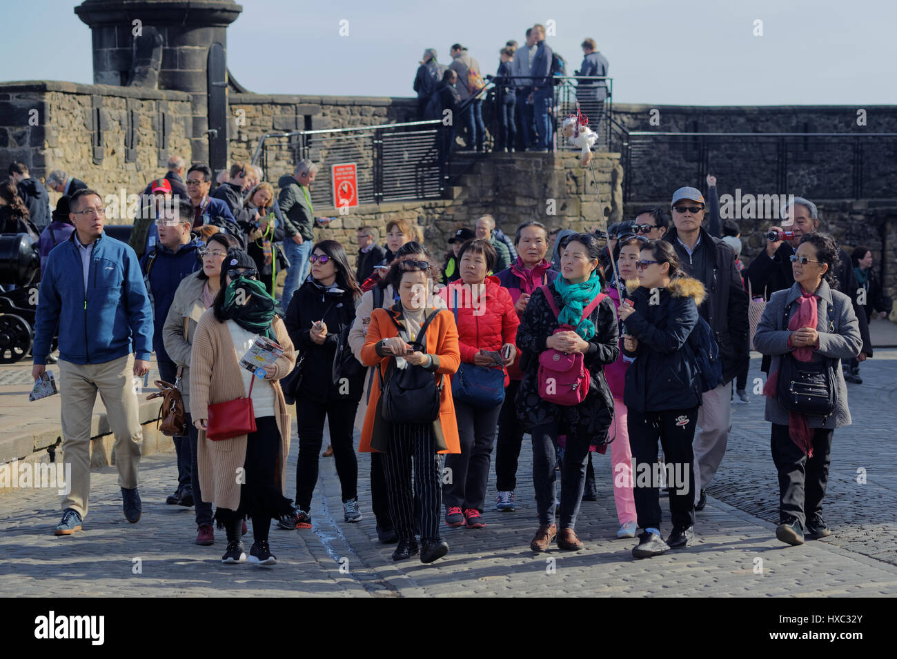 Edinburgh Castle tourist crowds on a sunny day explore the inside of the walls Japanese tourism party tour Stock Photo
