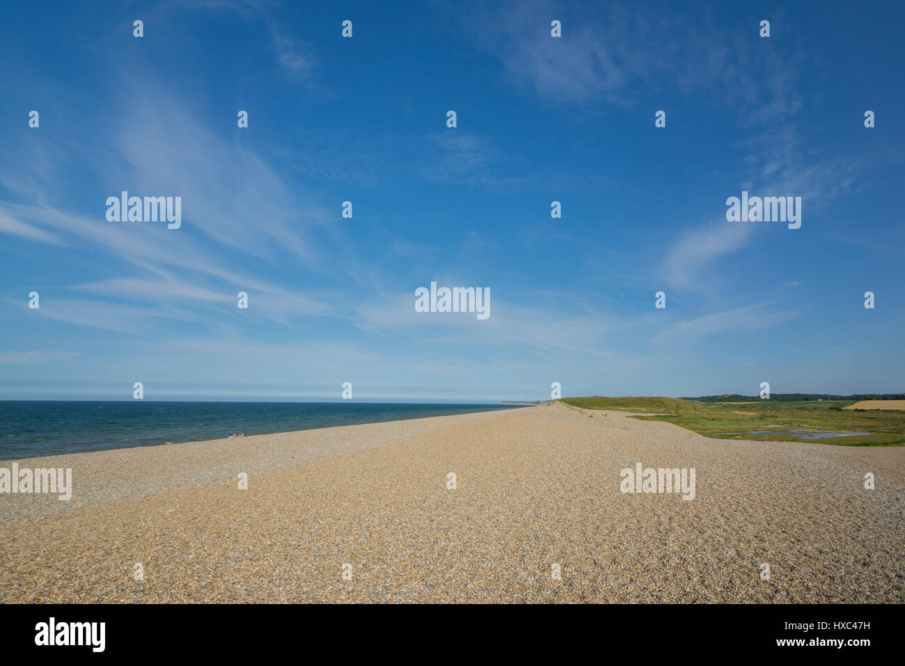 Norfolk coastline on the beech, pebbles with grasland, blue sky white clouds Stock Photo