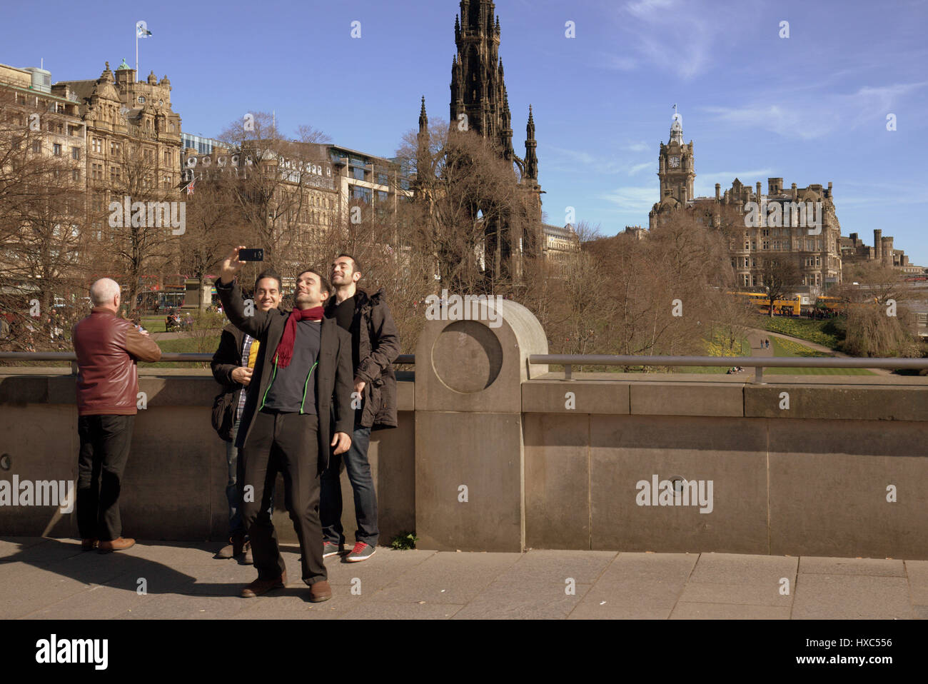 Tourists in princes street gardens at the National Museum of Scotland take selfies selfie selfy selfie with Edinburgh panorama as a backdrop Stock Photo