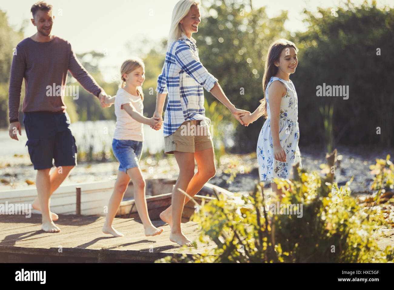 Barefoot family holding hands and walking on dock Stock Photo