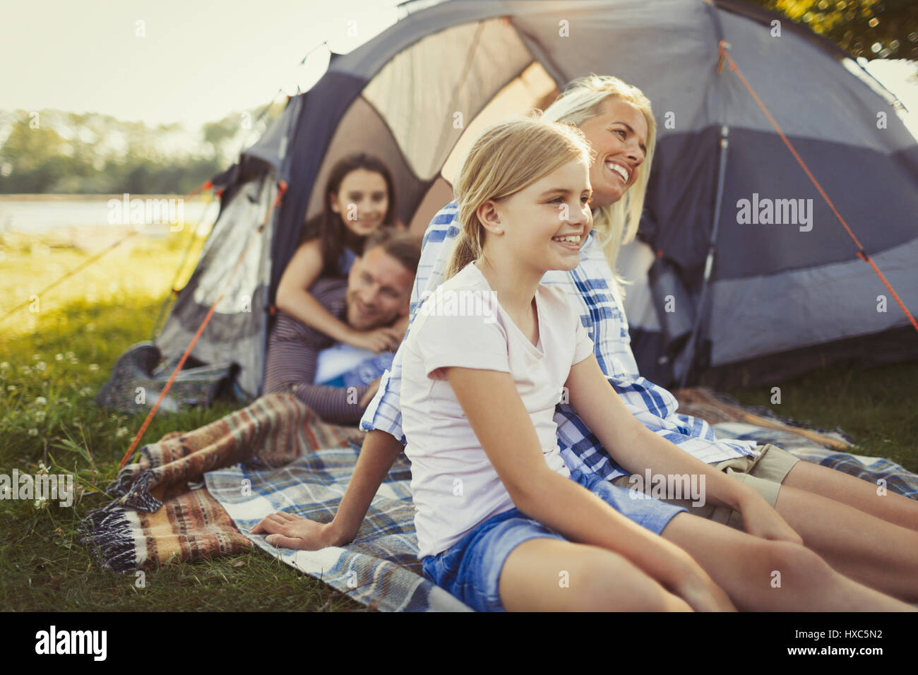 Smiling family relaxing outside campsite tent Stock Photo