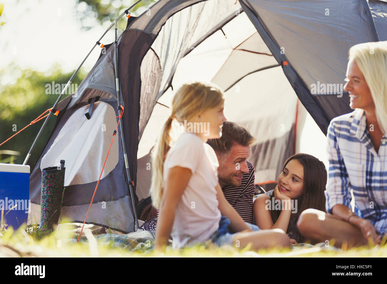 Smiling family talking and relaxing outside sunny tent Stock Photo