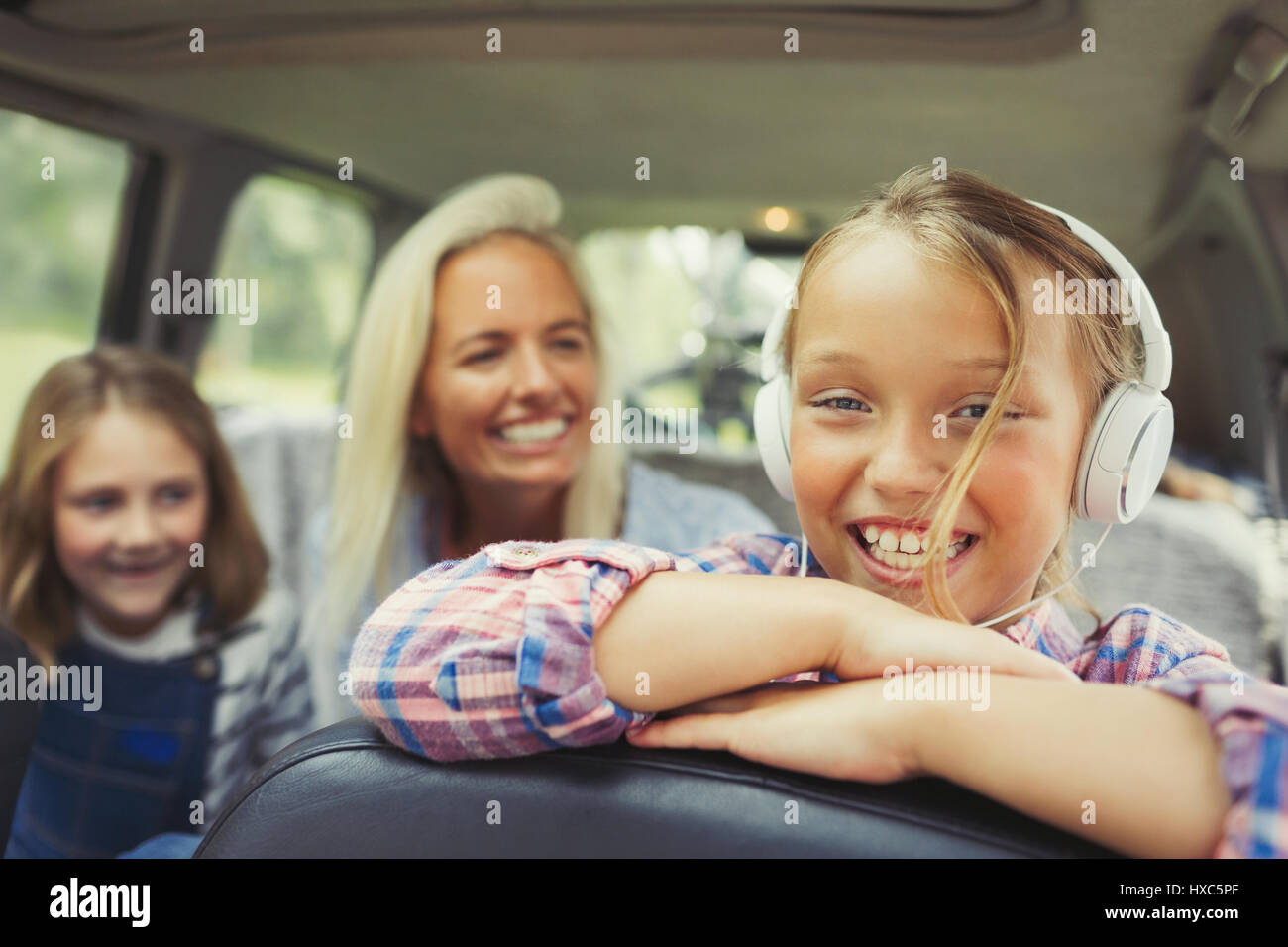 Portrait smiling girl wearing headphones in back seat of car Stock Photo