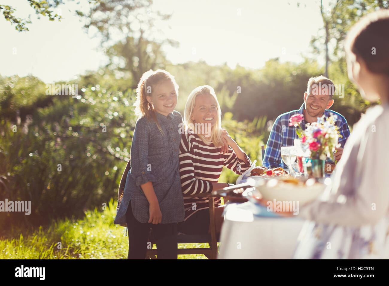 Happy family enjoying lunch at sunny garden party patio table Stock
