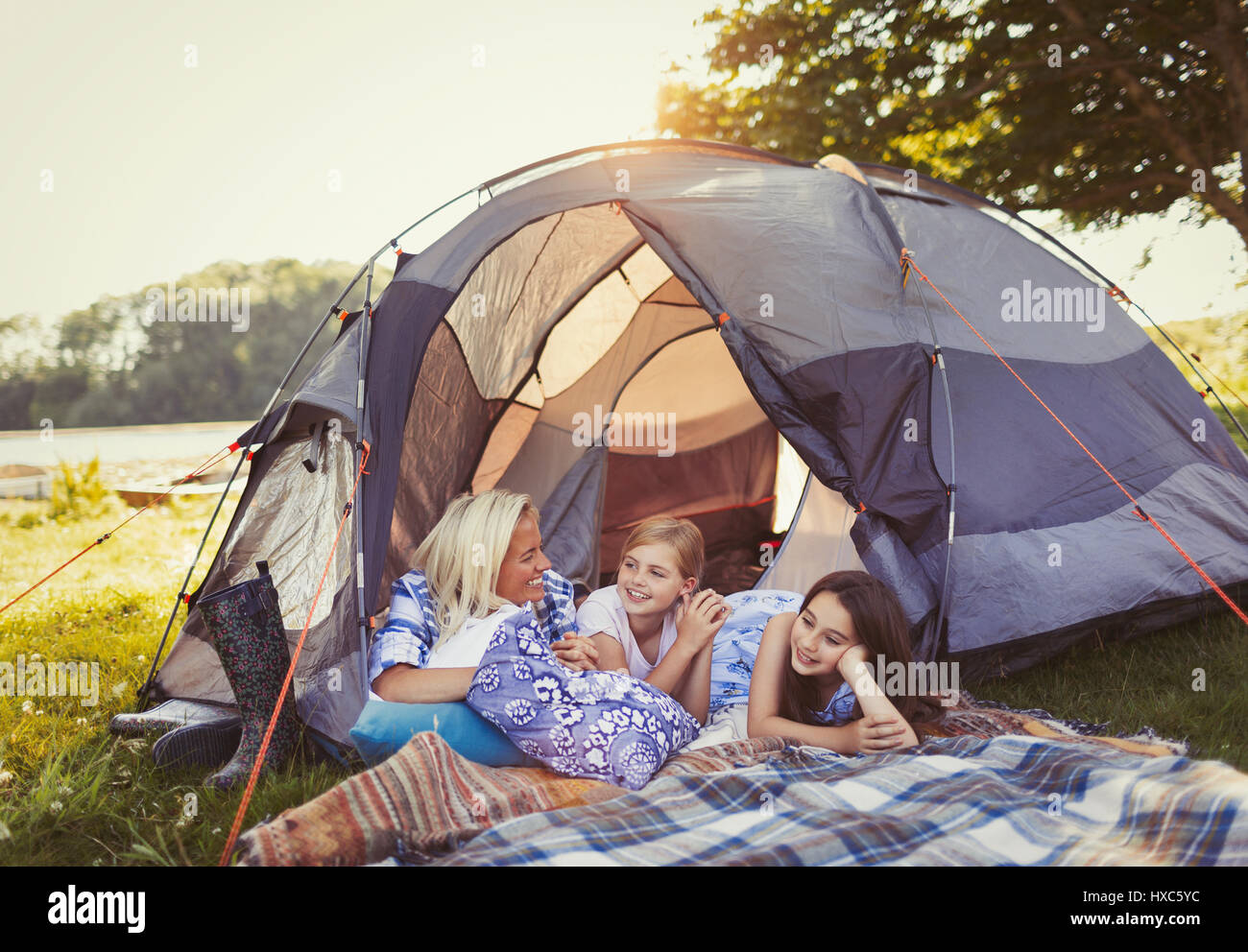 Mother and daughters talking and relaxing in tent at campsite Stock Photo