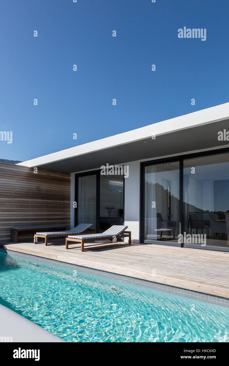 Sunny modern luxury home showcase exterior patio and lap swimming pool ...