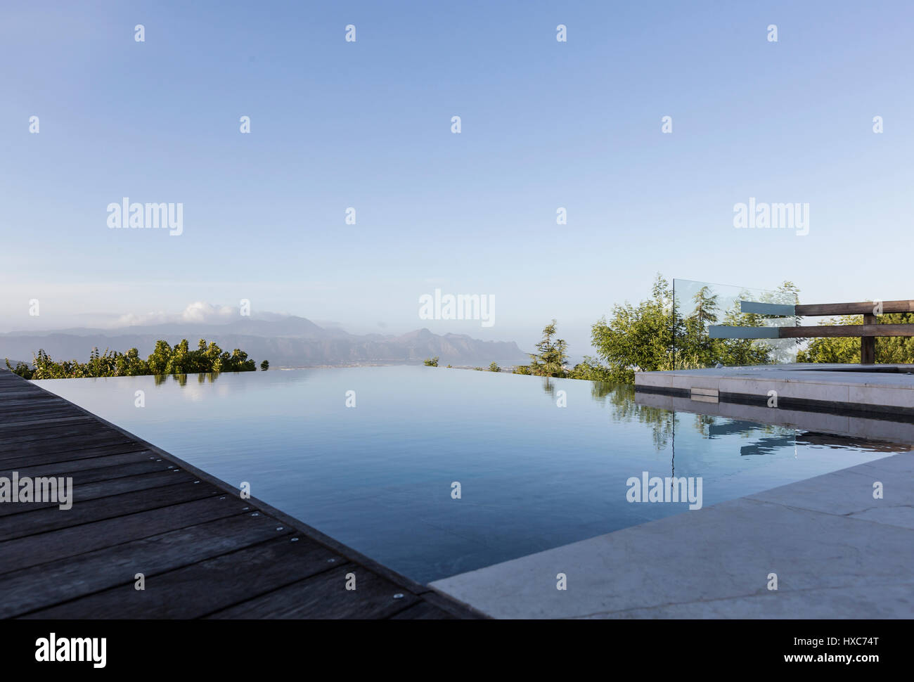 Tranquil luxury infinity pool with mountain view below blue sky Stock Photo