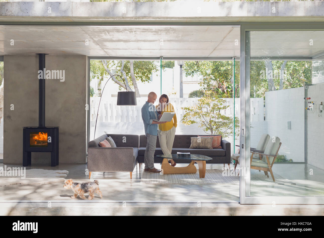 Couple using laptop in modern living room open to patio Stock Photo - Alamy