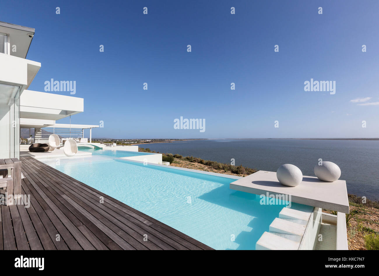 Sunny, tranquil modern luxury home showcase exterior infinity pool with ...