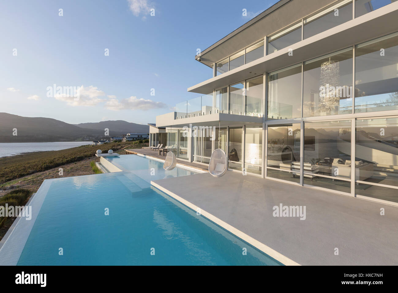 Sunny, tranquil modern luxury home showcase exterior with infinity pool ...