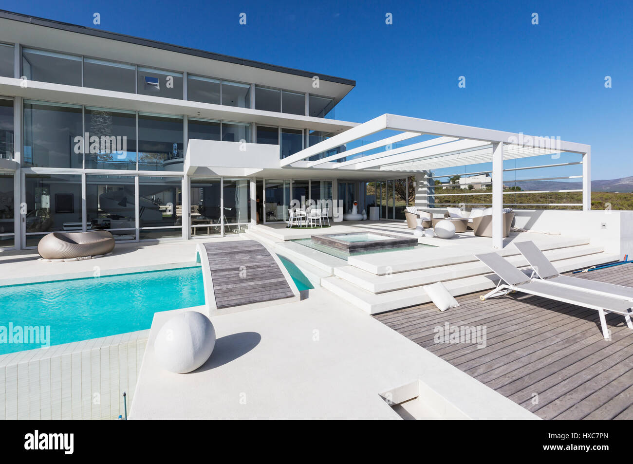 Sunny modern luxury home showcase exterior with lounge chairs and ...