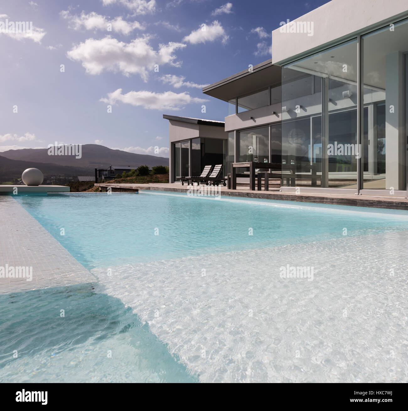 Sunny, tranquil modern luxury home showcase exterior with swimming pool ...