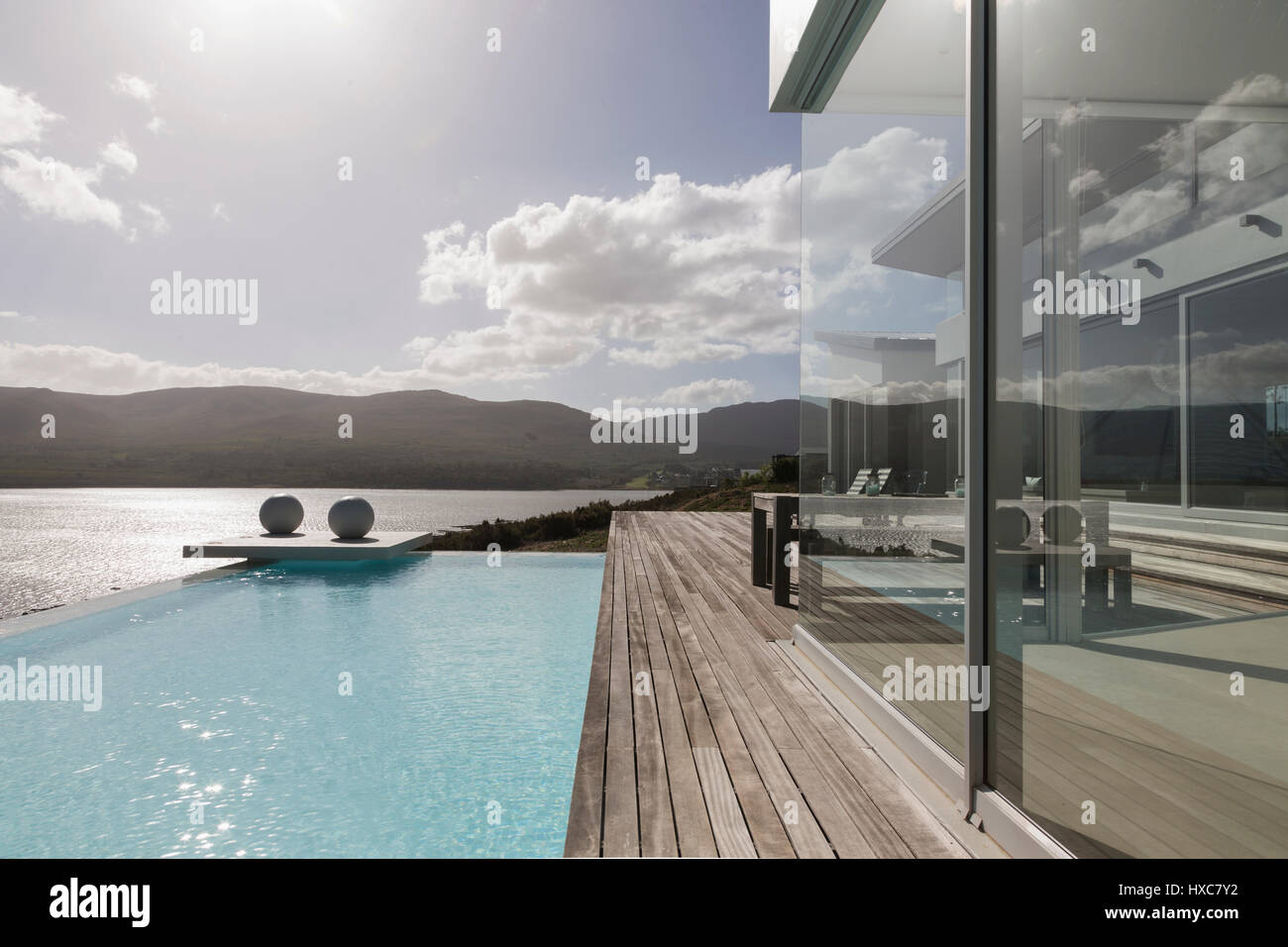 Sunny, tranquil modern luxury home showcase exterior with infinity pool ...