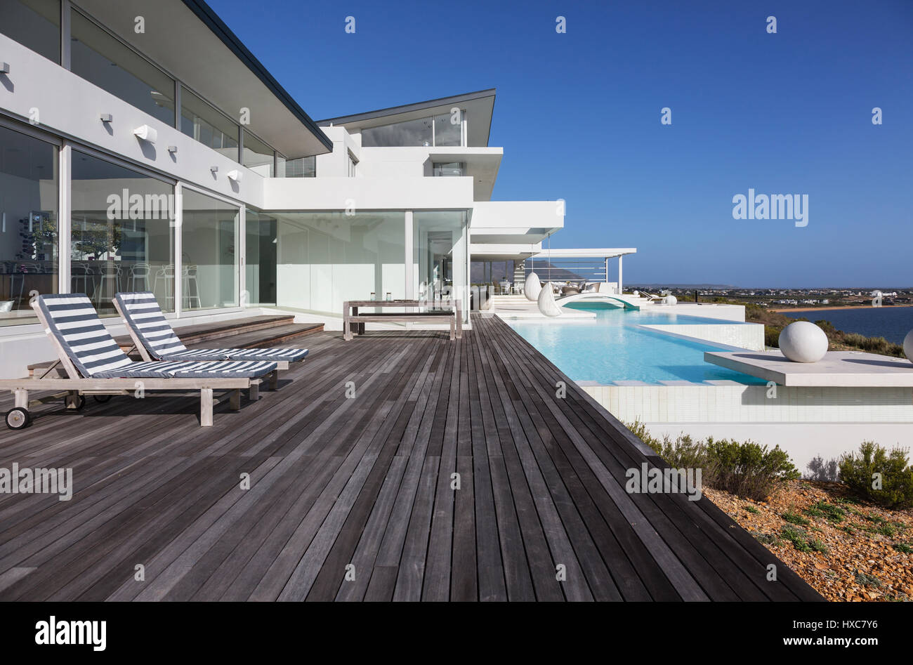 Sunny modern luxury home showcase exterior patio with infinity pool ...