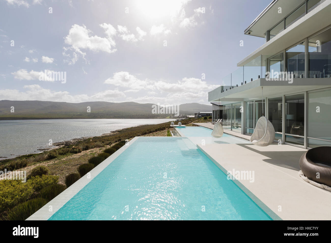 Sunny, tranquil modern luxury home showcase exterior with infinity pool ...