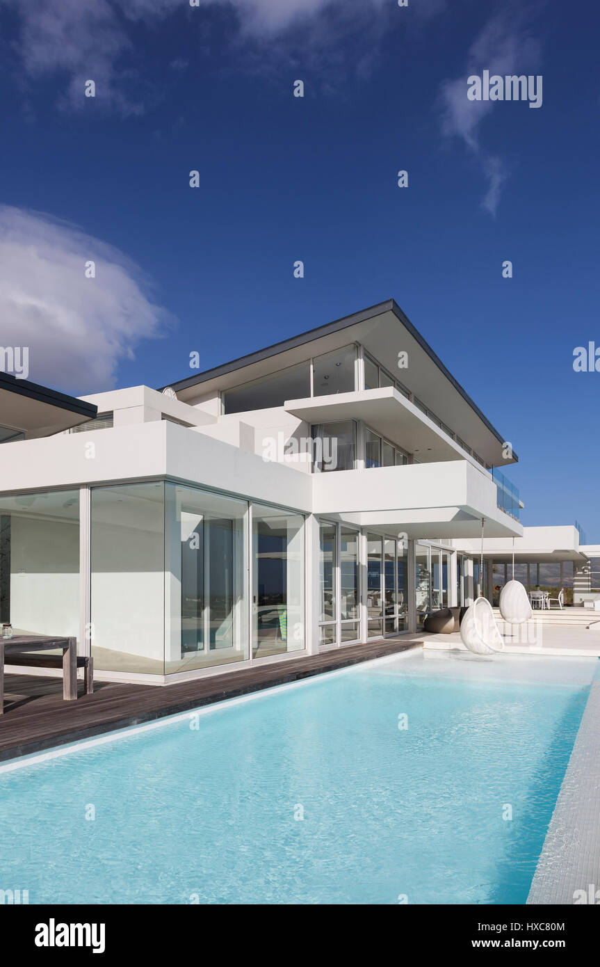 Sunny, tranquil modern luxury home showcase exterior with swimming pool ...