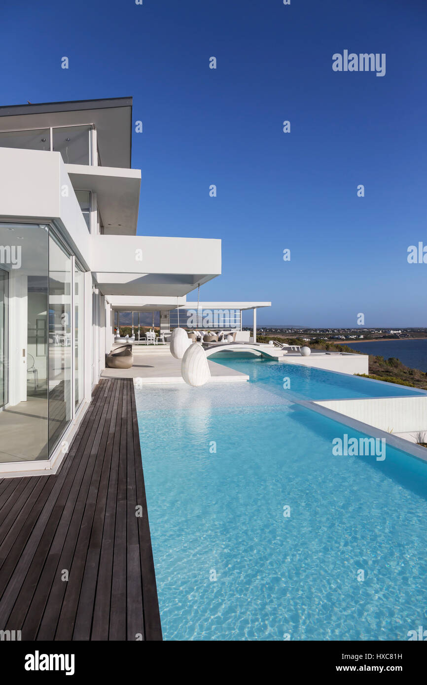 Sunny, tranquil modern luxury home showcase exterior with infinity pool ...