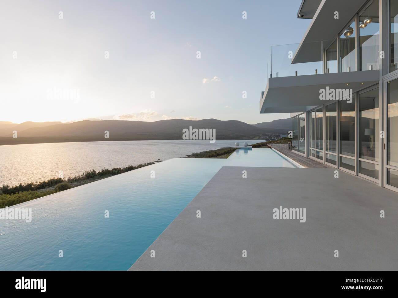 Sunny, tranquil modern luxury home showcase exterior with infinity pool and sunset ocean view Stock Photo