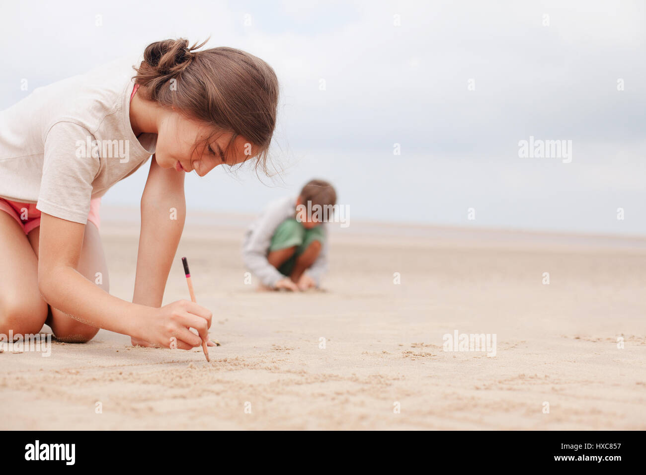 Girl with stick writing in sand on summer beach Stock Photo Alamy