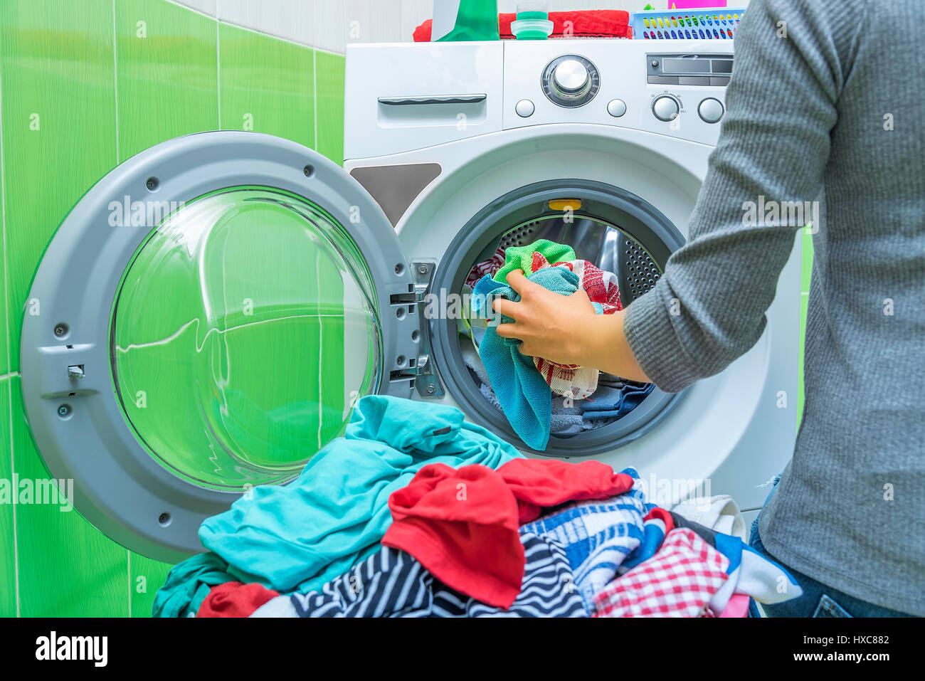 Preparing the wash cycle. Washing machine, hands and clothes Stock