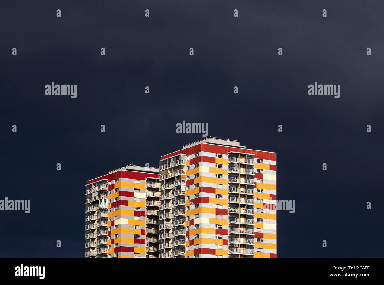 Two colorful residential buildings against stormy dark blue sky. Abstract looking high contrast picture with copy space on the top Stock Photo