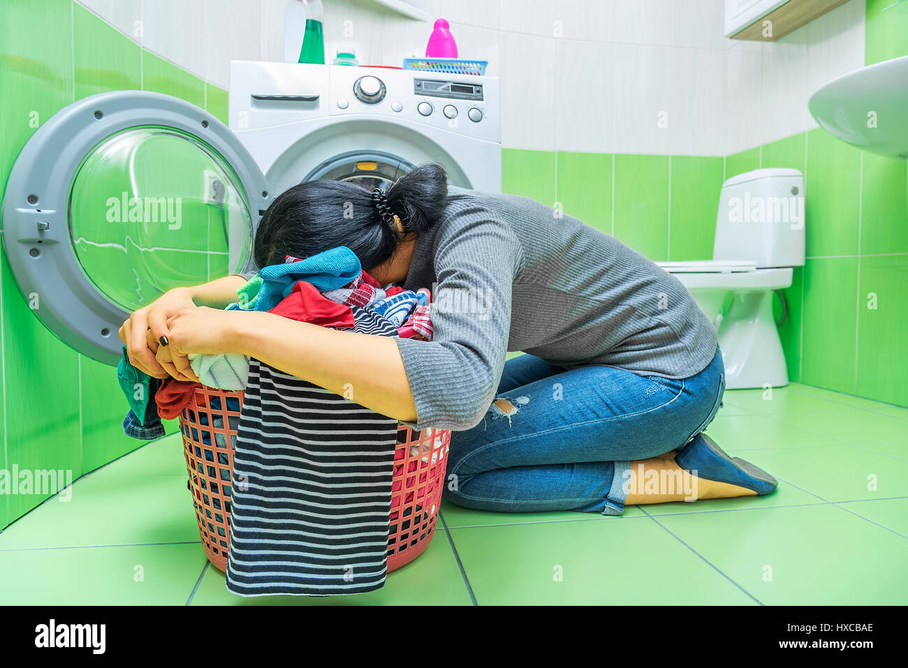 Woman tired of washing. She's lying on the laundry basket. Stock Photo