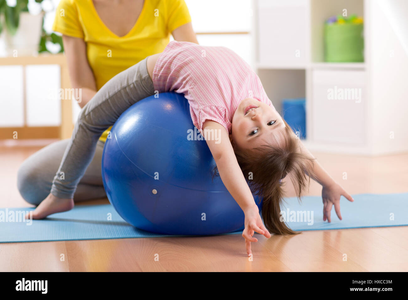 Cute child girl stretching on pilates fitness ball in gym Stock Photo