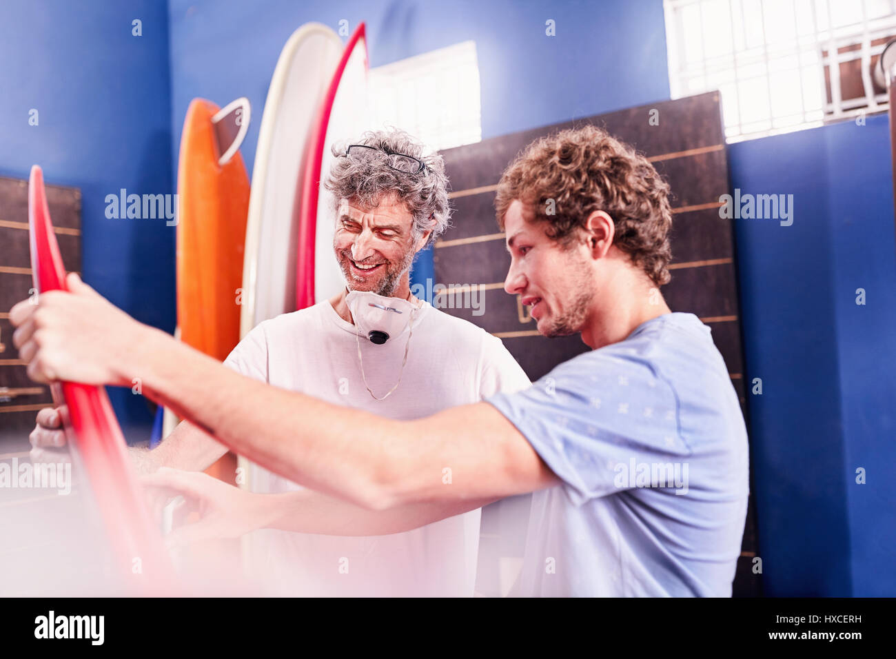 Men making and discussing surfboards in workshop Stock Photo