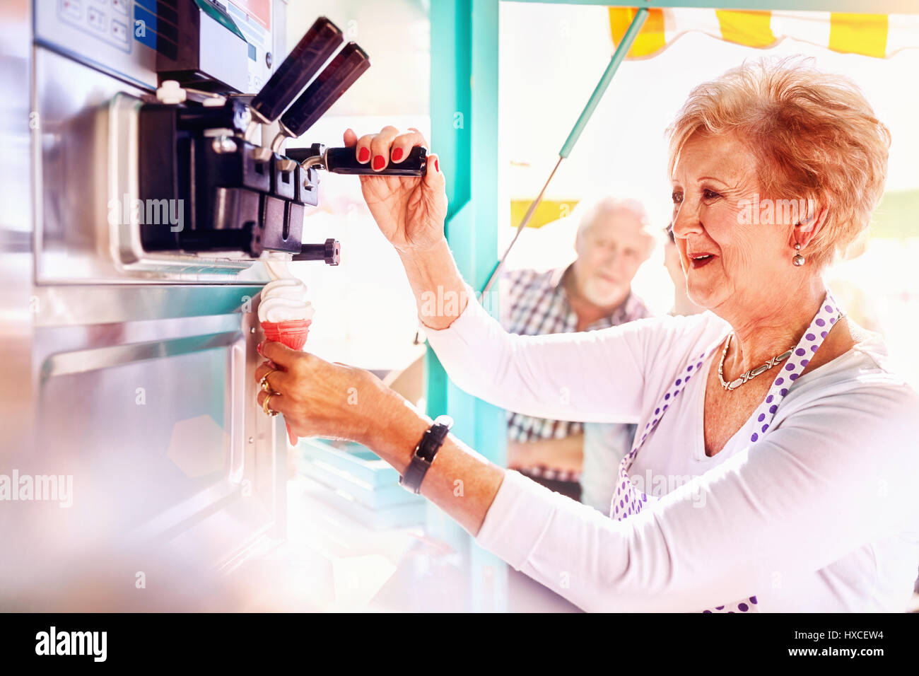 Senior female business owner serving ice cream at food cart Stock Photo