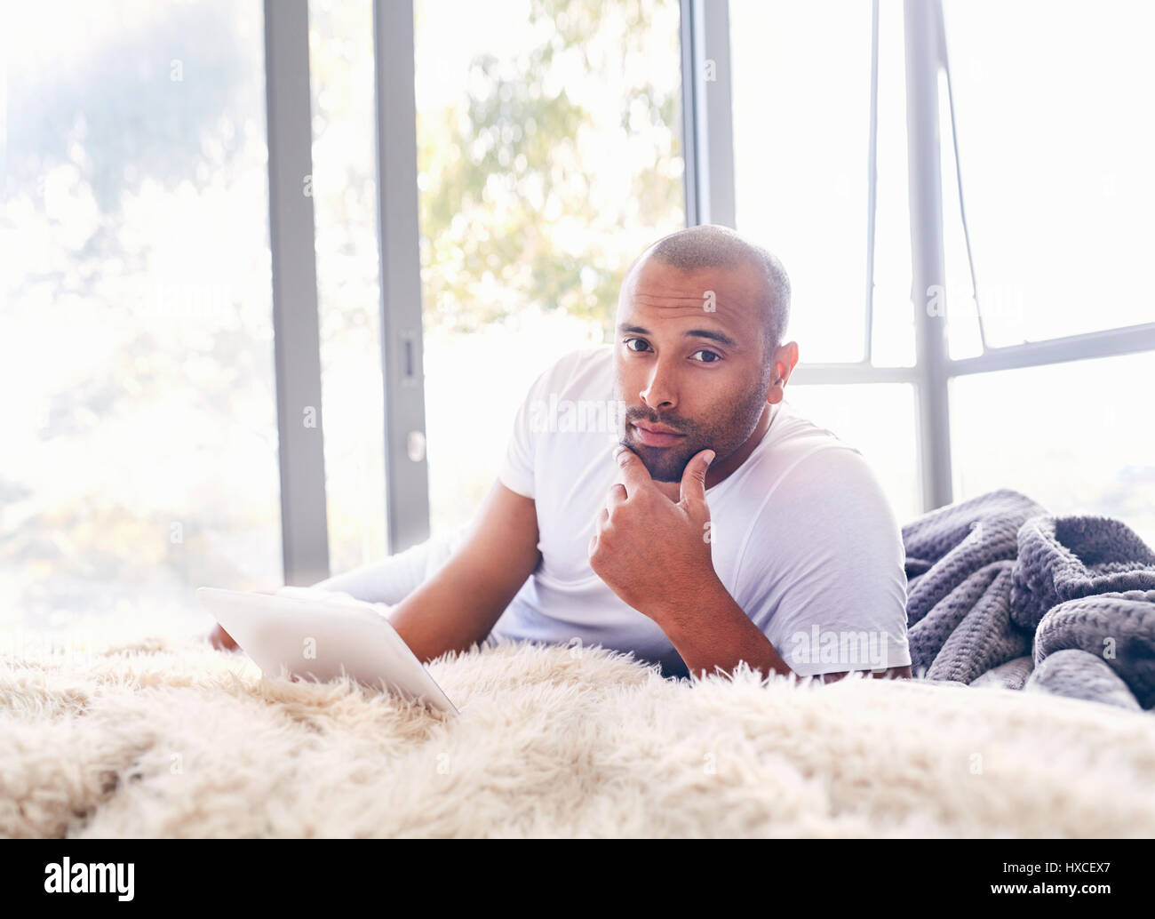 Portrait serious handsome man using digital tablet on bed Stock Photo