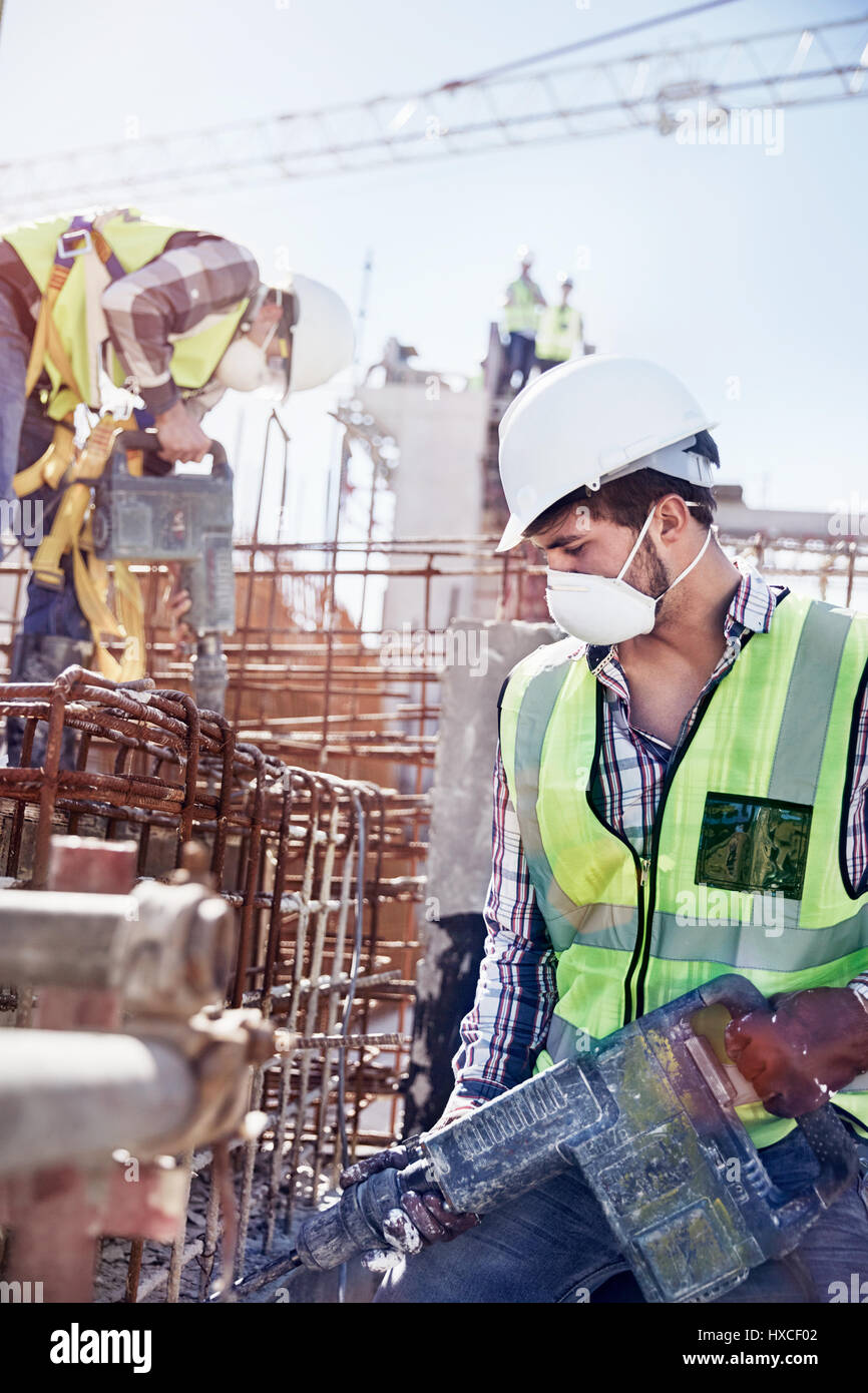 Construction worker wearing protective mask at sunny construction site Stock Photo
