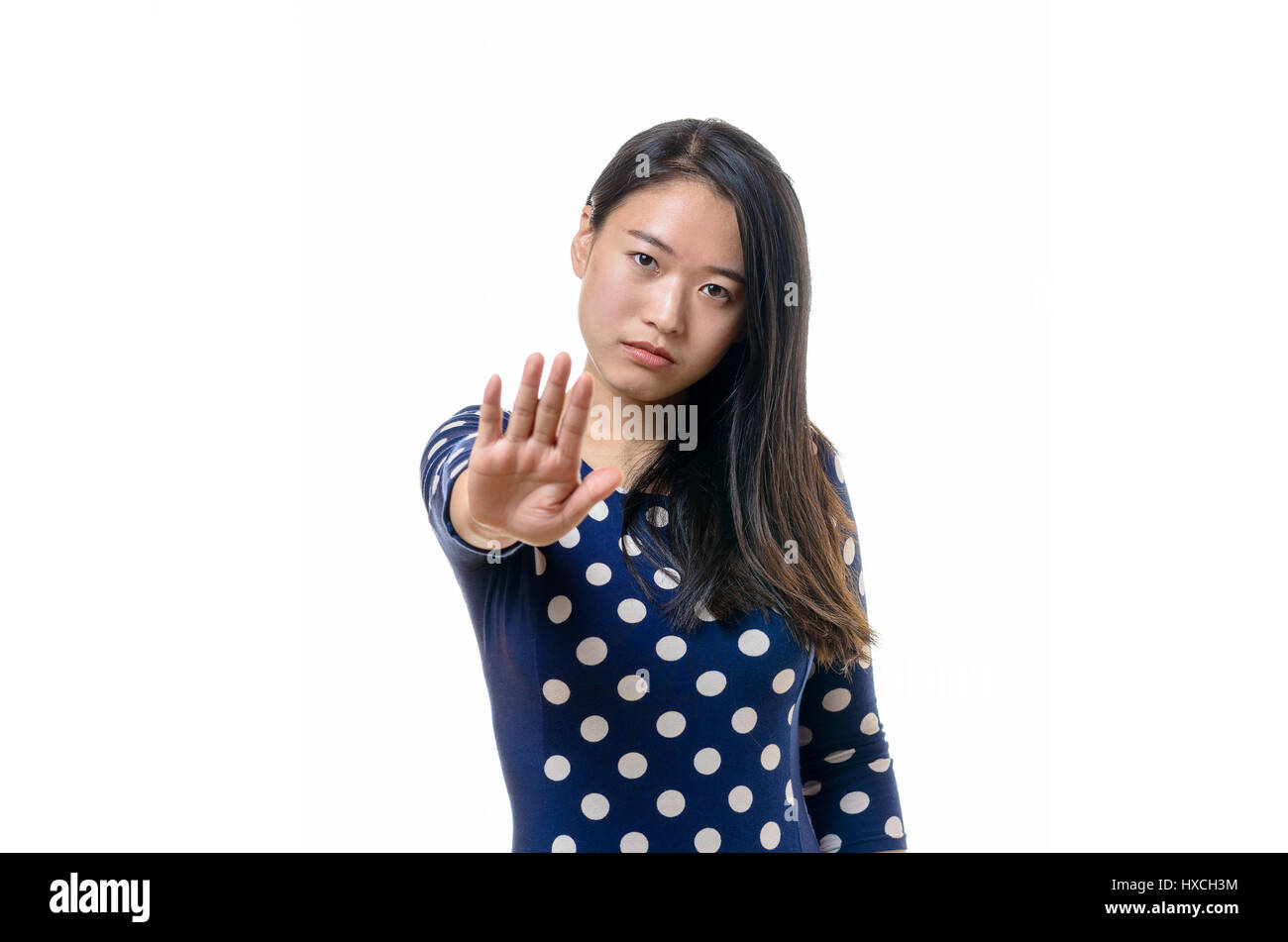 Angry stern young Chinese woman making a halt, enough or go away gesture with the palm of her hand, upper body isolated on white Stock Photo