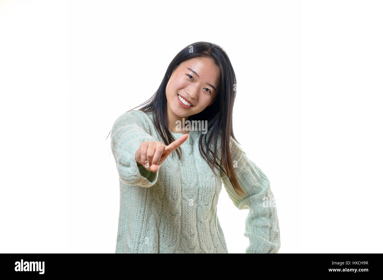 Cute young Chinese woman wagging her finger at the camera admonishing the viewer with a sweet friendly smile, isolated on white Stock Photo