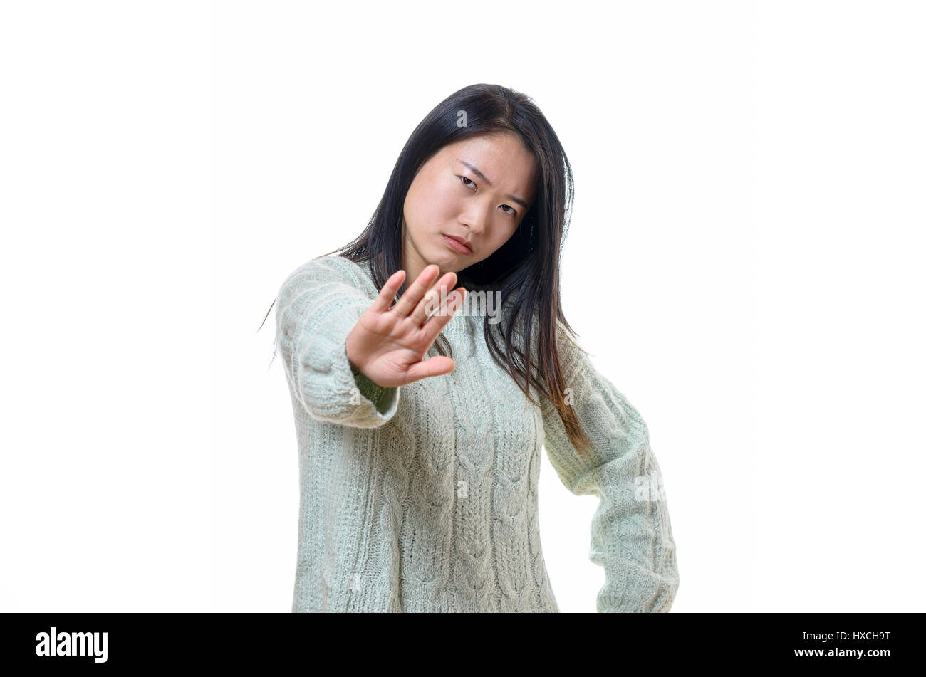 Angry stern young Chinese woman making a halt, enough or go away gesture with the palm of her hand, upper body isolated on white Stock Photo