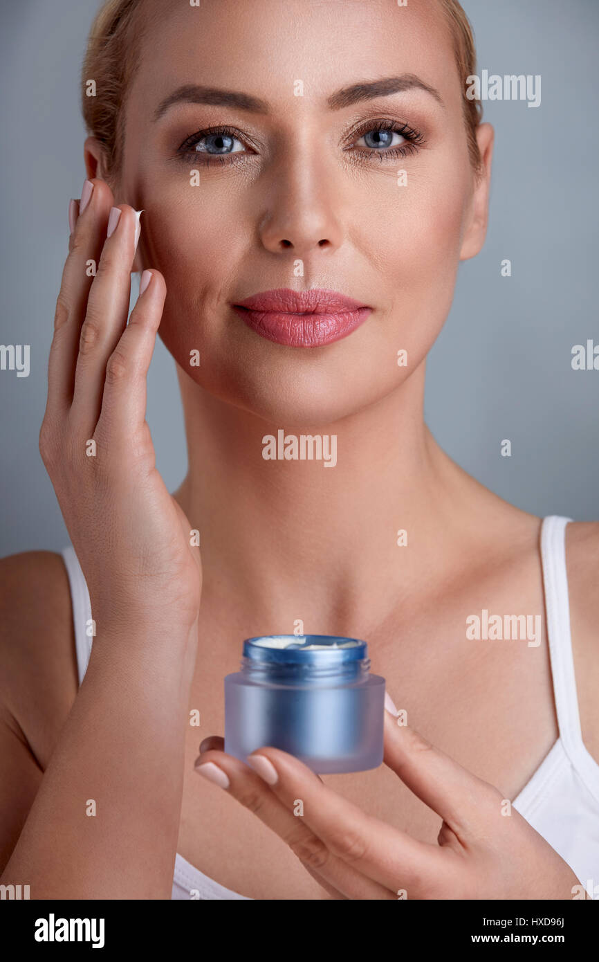 Middle aged woman uses the cream to rejuvenate skin cells Stock Photo