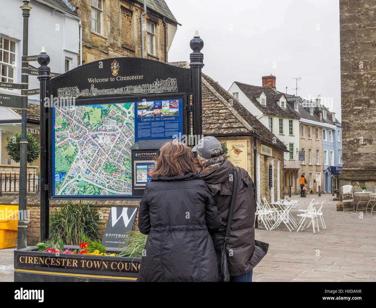 a couple man and woman looking at a map on a board in the new pedestrian area in the centre center of Cirencester Stock Photo