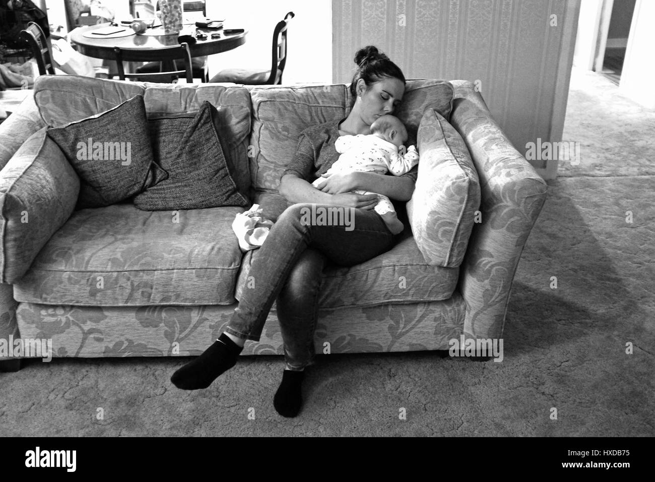 Young woman and baby asleep on the sofa at home Stock Photo