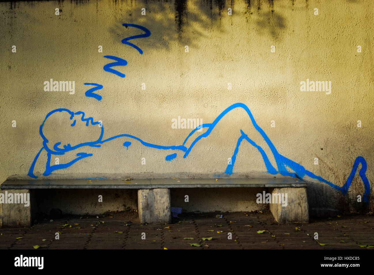 a graffiti of a man sleeping on a bench Stock Photo
