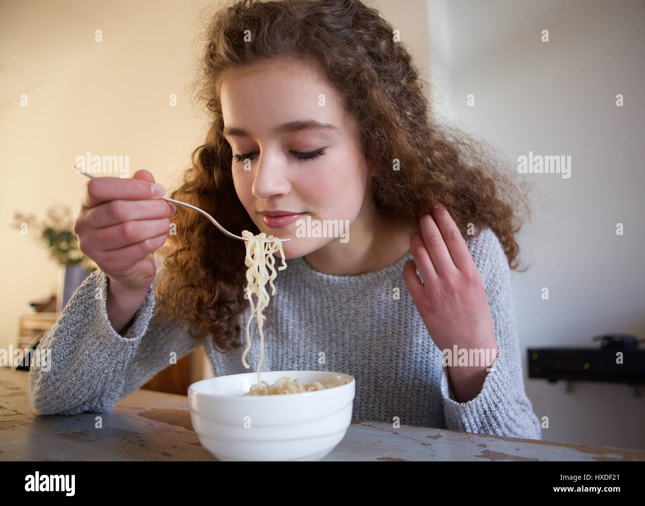 Close up portrait of a teenage girl eating noodles at home Stock Photo