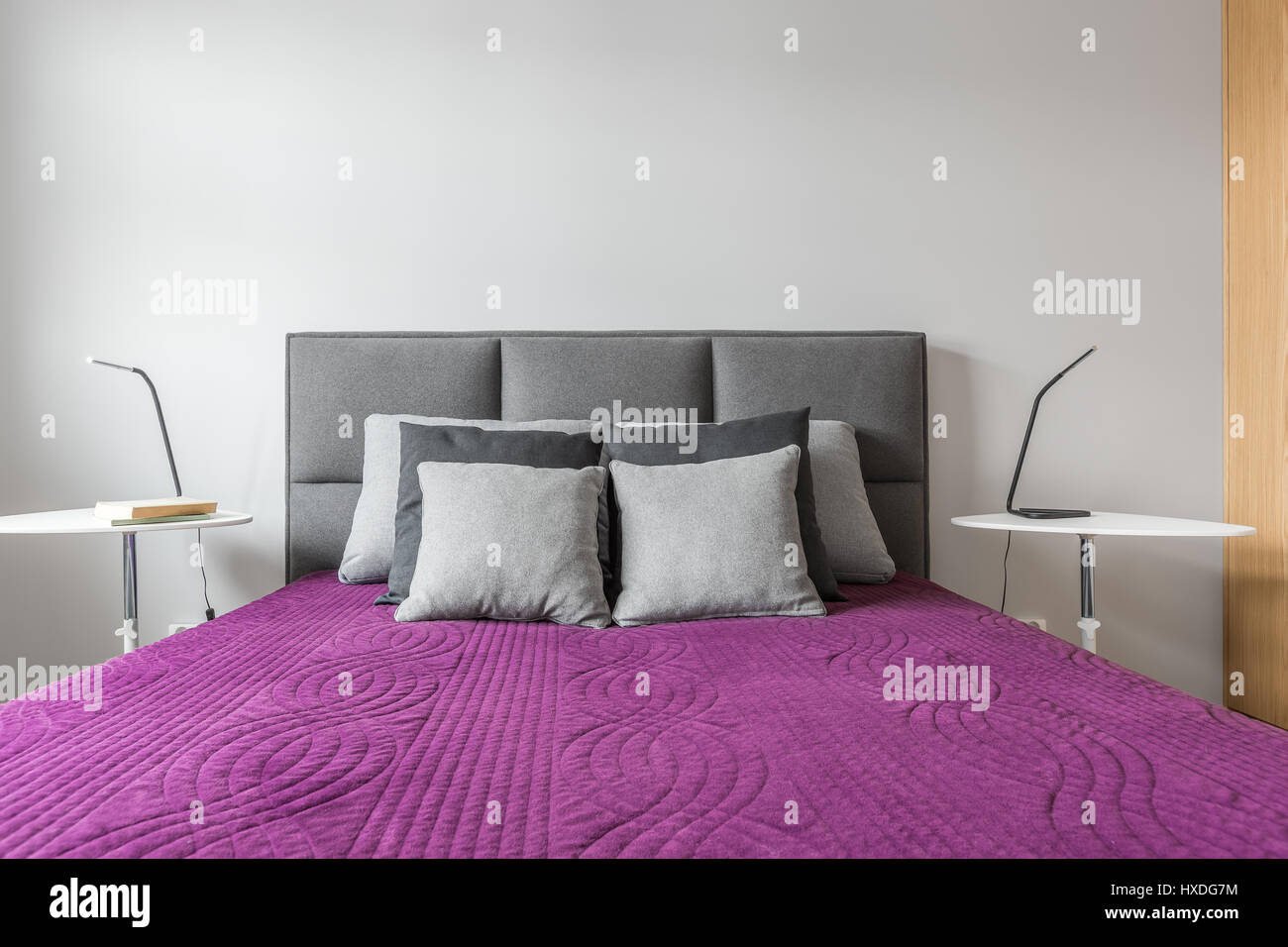 https://c8.alamy.com/comp/HXDG7M/big-bed-with-grey-decorative-pillows-and-purple-bedcover-in-modern-HXDG7M.jpg