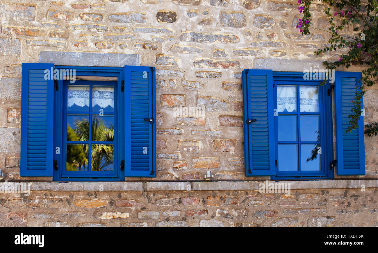 View of a traditional Bodrum house. Stone walls, blue windows and shutters reflect the architectural style of the region. It shows Aegean / Mediterran Stock Photo