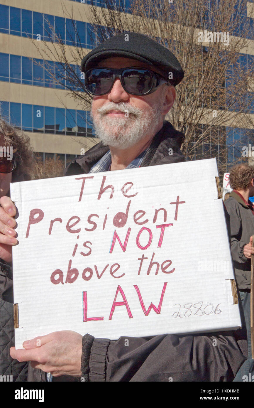 Asheville, North Carolina, USA - February 25, 2017: Senior man at a rally for Obamacare holds a sign saying 'The President is NOT Above the LAW' on Fe Stock Photo