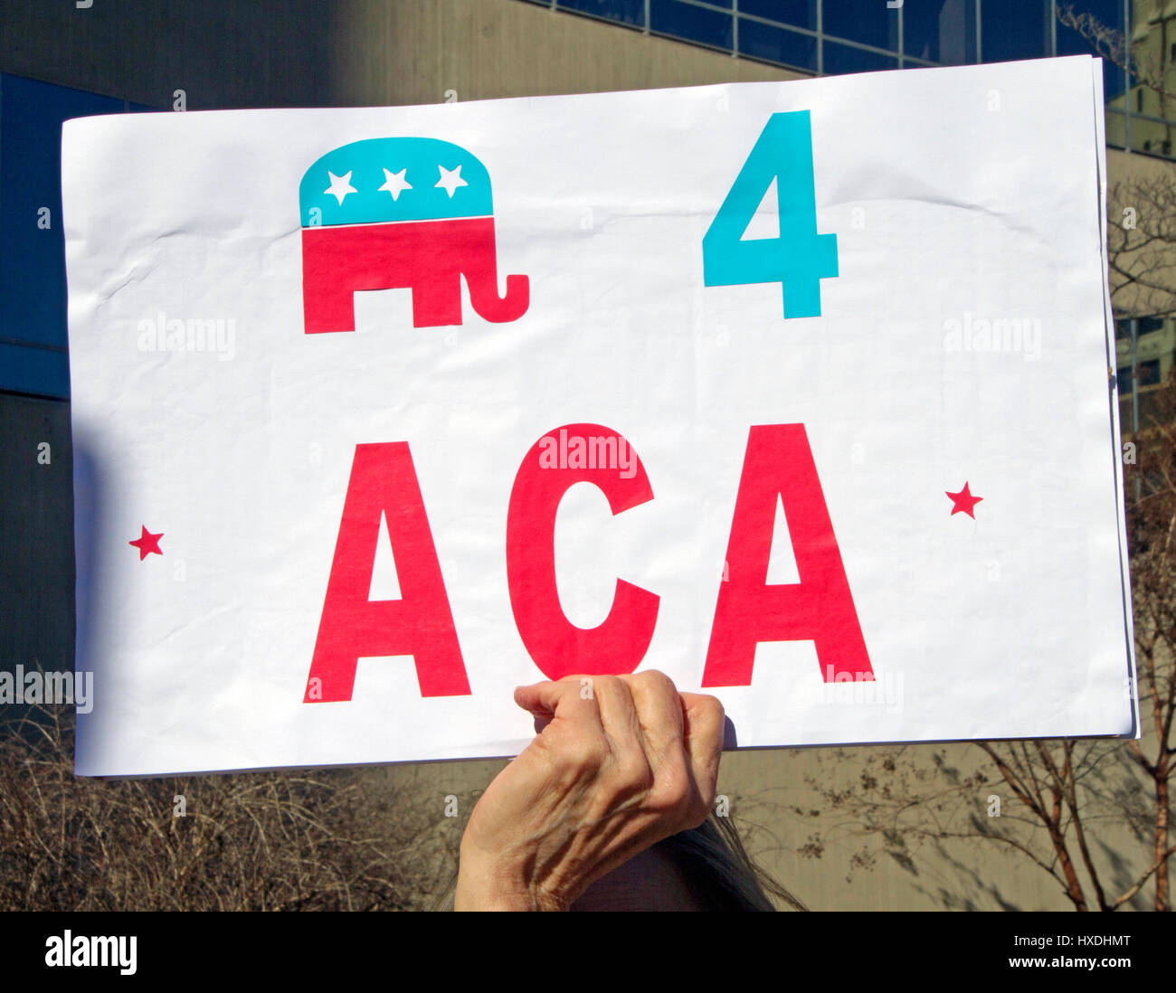 Asheville, North Carolina, USA - February 25, 2017: Close up of a hand holding a colorful sign at an Obamacare rally that shows the GOP (a Republican) Stock Photo