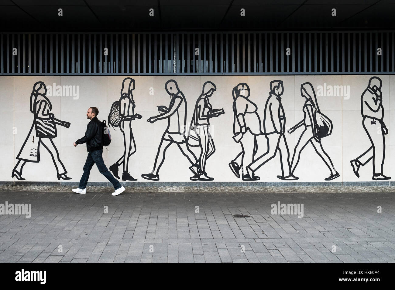 Pedestrian walking past a mural Artwork Public Art Wall Figures London Stock Photo