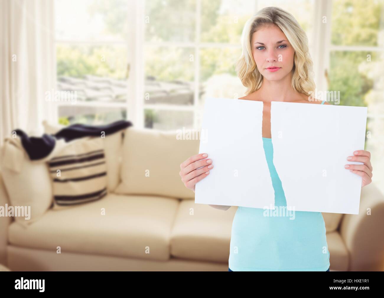 Digital composite of melancholic woman ripping paper in two in sitting room Stock Photo