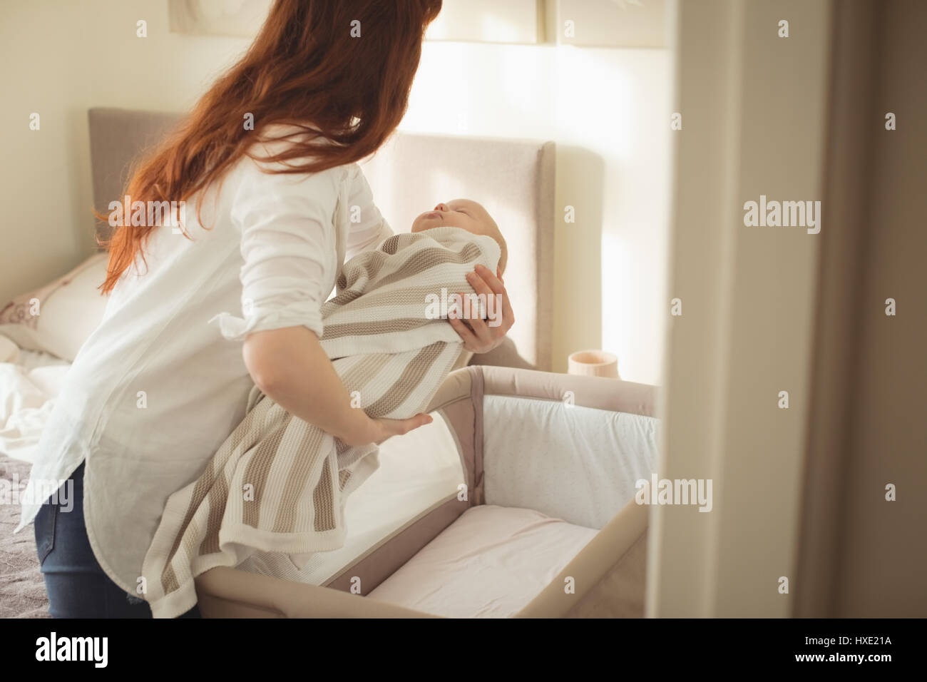 Mother laying baby in crib at home Stock Photo Alamy