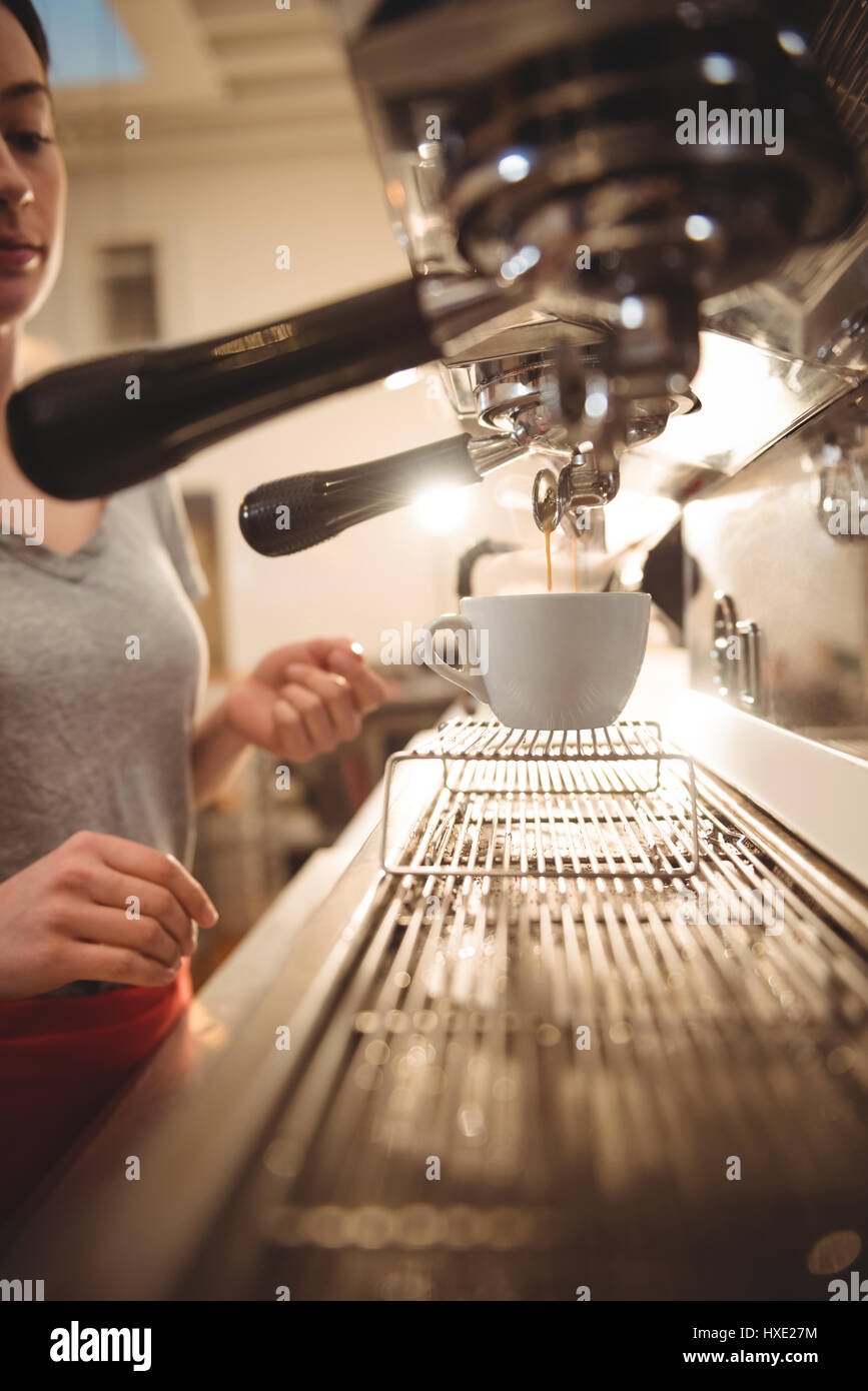 Cropped image of female barista making coffee using espresso machine in cafe Stock Photo